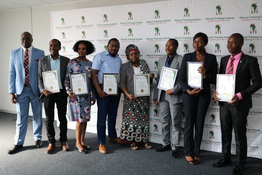 African Training Institute certificate award ceremony with graduates holding certificates in front of ATI branded backdrop